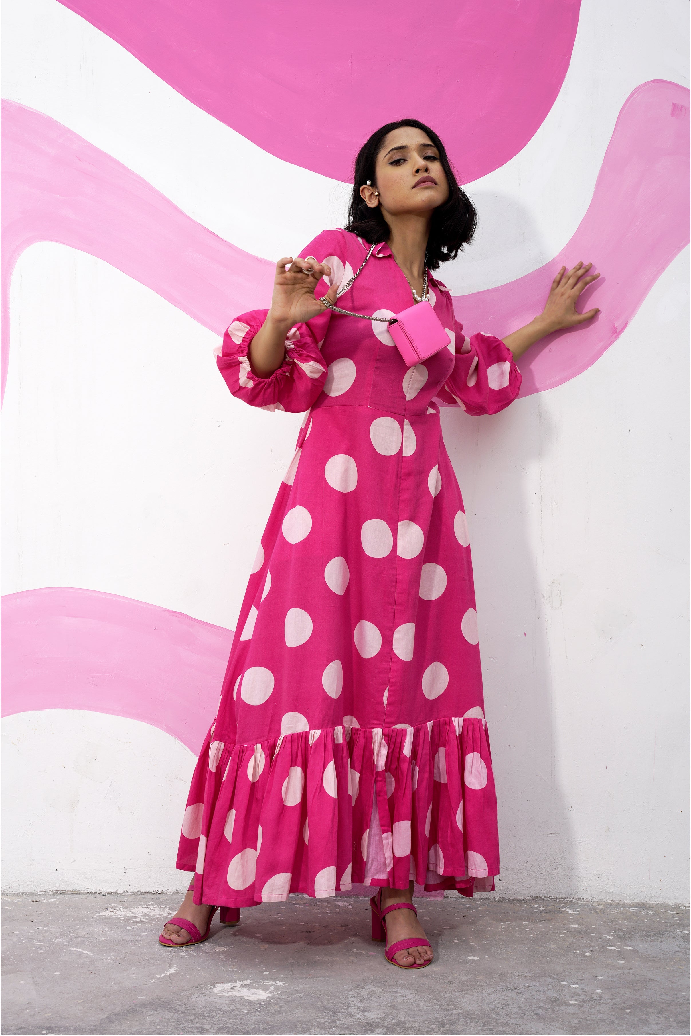 Model wearing Aine's polka dot midi dress with a pink purse, full body shot