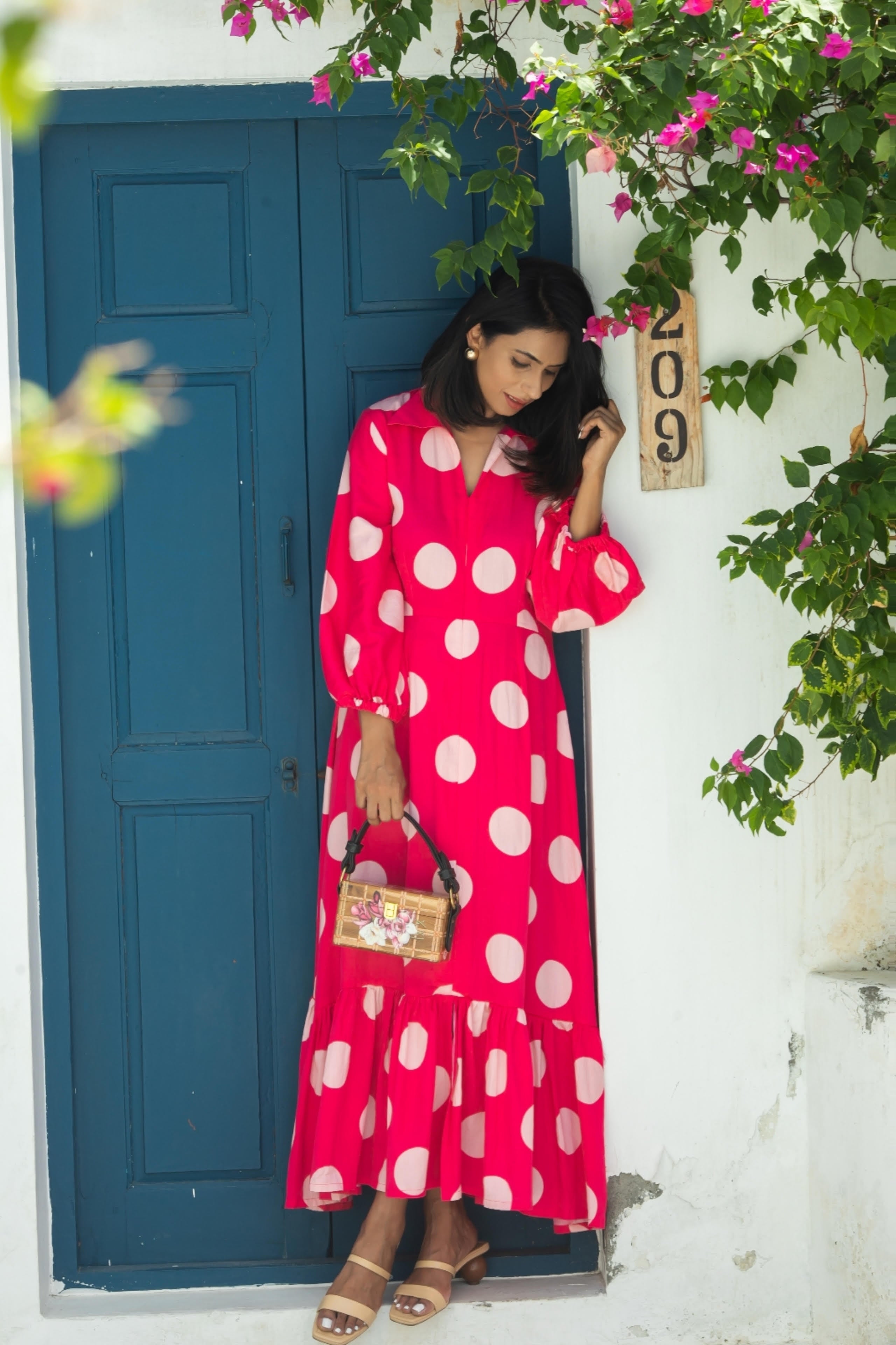 Model wearing Aine's polka dot midi dress with a purse, full body shot